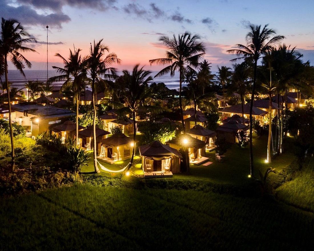 The glamping village lit up at dusk by the ocean