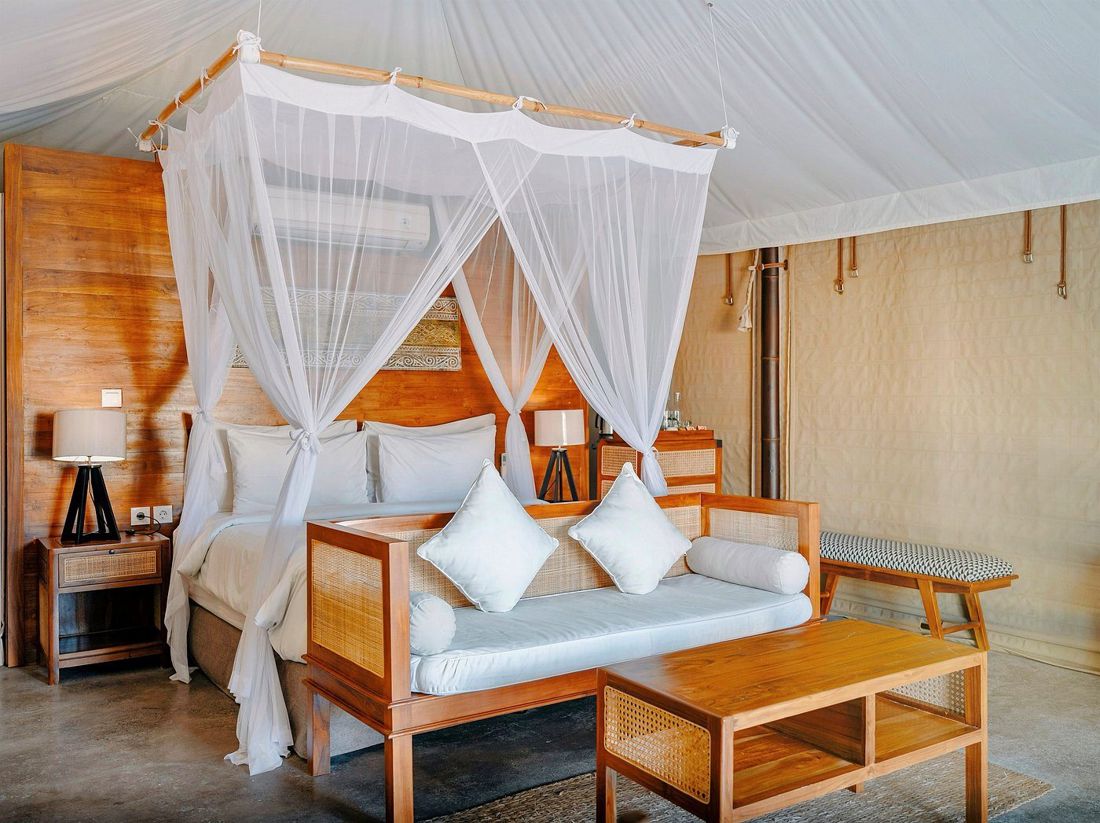 A canopy bed and daybed inside a glamping tent