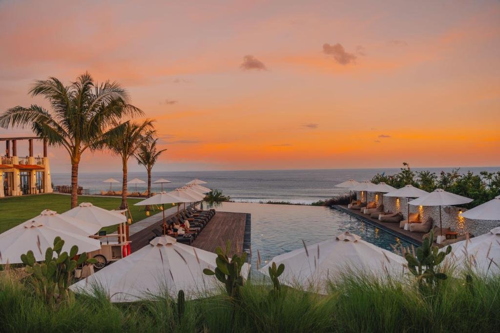 Clifftop infinity pool with umbrellas at sunset